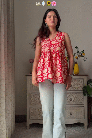 Women’s Sleeveless Red Floral Top with Light Blue Flared Jeans – Indo-Western Casualwear Styled with Vintage Decor Backdrop